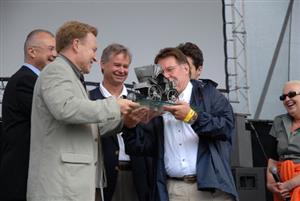 Šéf Tatry Ronald Adams přebírá dárek od starosty města. Předání modelu prvního vozu  přihlížel také velvyslanec Spojených států amerických Richard Graber (uprostřed).