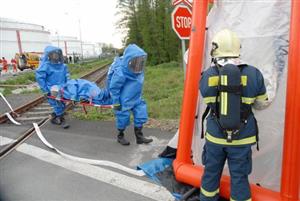 Hasiči v ochranných oblecích v rámci cvičení simulují záchranu kolegy, který při zásahu zkolaboval.<br/>
FOTO: DAVID MACHÁČEK
