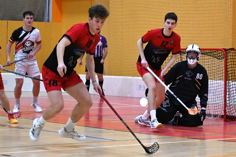 Ošemetnou situaci před brankou Mikuláše Kaliny řeší domácí florbalisté Jakub Kűffer (č. 18) a Vojtěch Blažek (12).